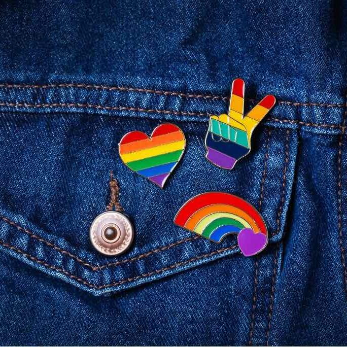 Three rainbow pins on a denim jacket. Glisten Events